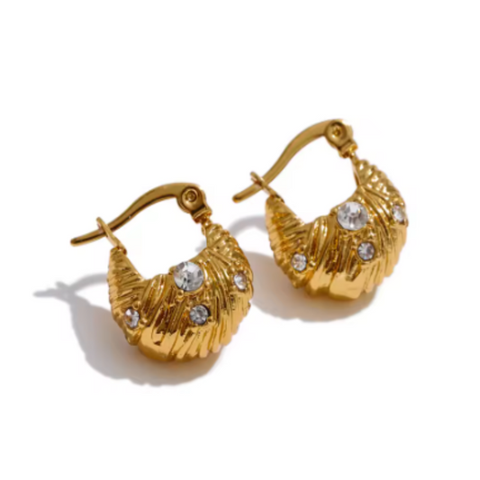 A pair of gold crescent-shaped hoop earrings with textured leaf-like detailing and small clear rhinestones, shown on a white background with soft shadows.