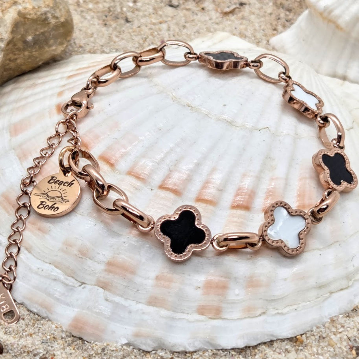 Rose gold bracelet with black and white charms on a seashell