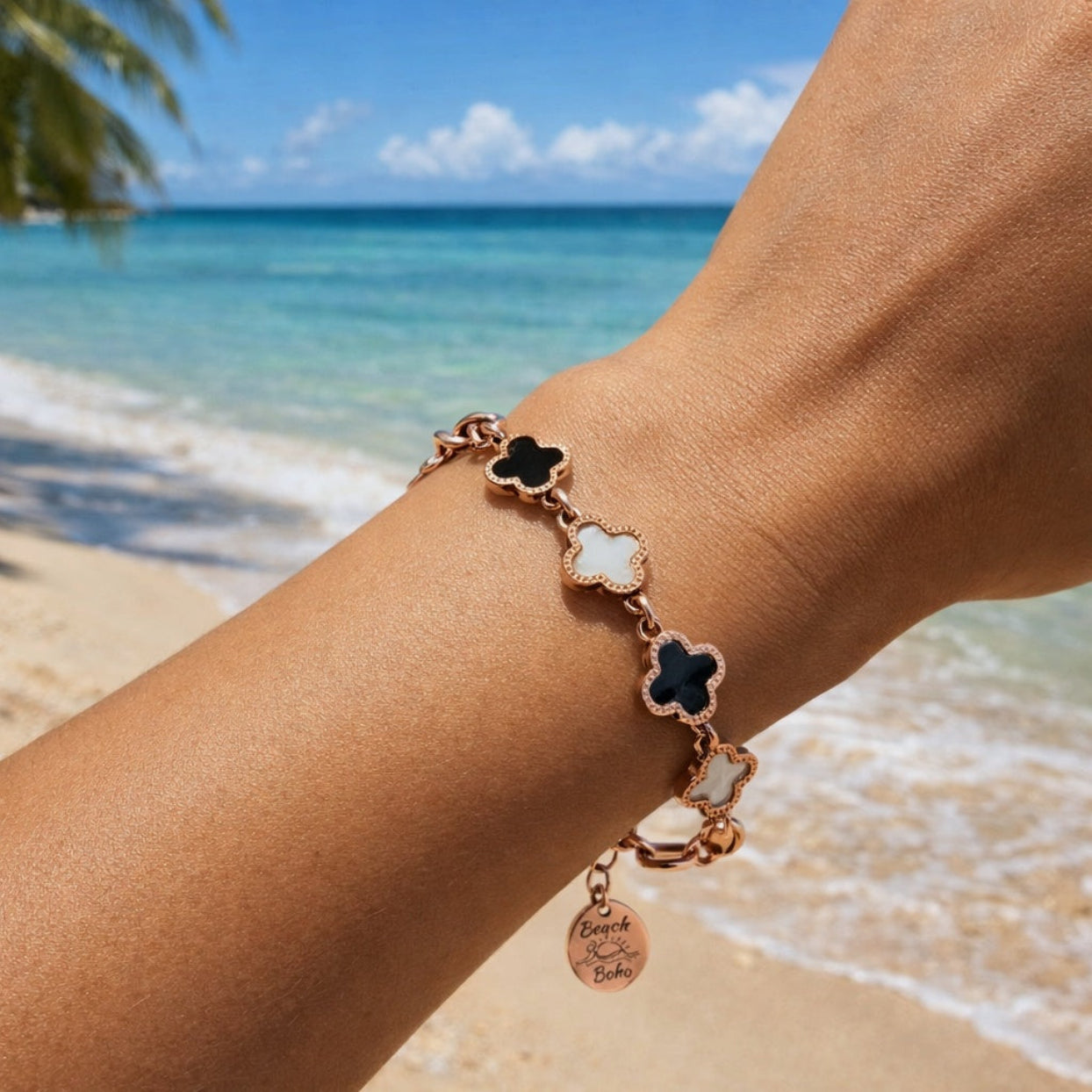 Bracelet with clover charms on a wrist by the ocean