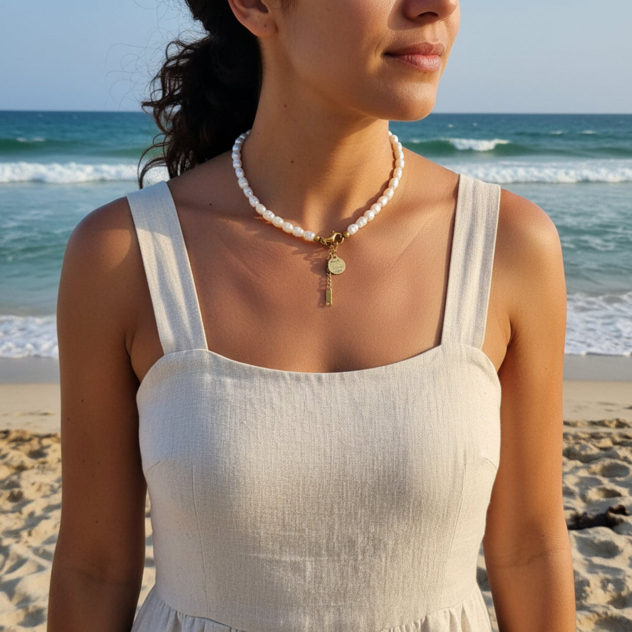Woman wearing a pearl necklace with a beach in the background