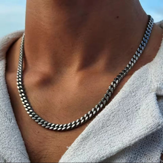 Close-up of a person wearing a silver chain necklace with a blurred background