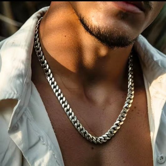 Close-up of a person wearing a silver chain necklace with a blurred background