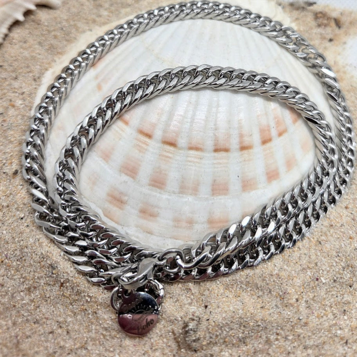 Silver chain bracelet with a heart charm on a seashell