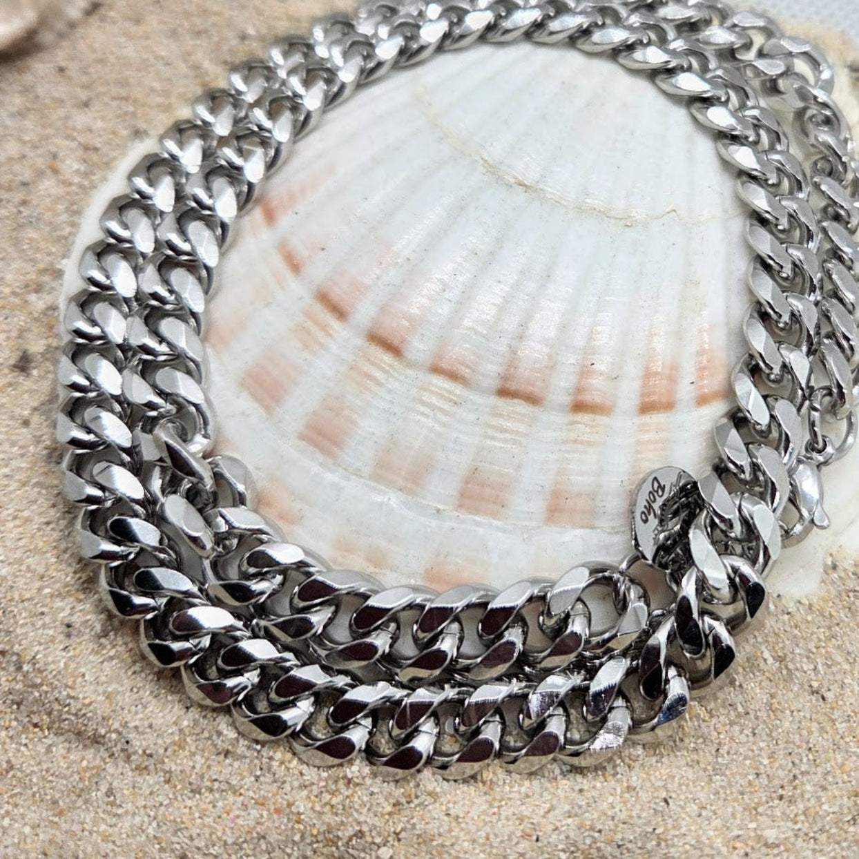 Silver chain bracelet on a seashell with sand background