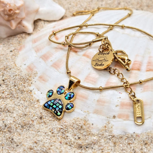 Gold necklace with paw print pendant on a shell