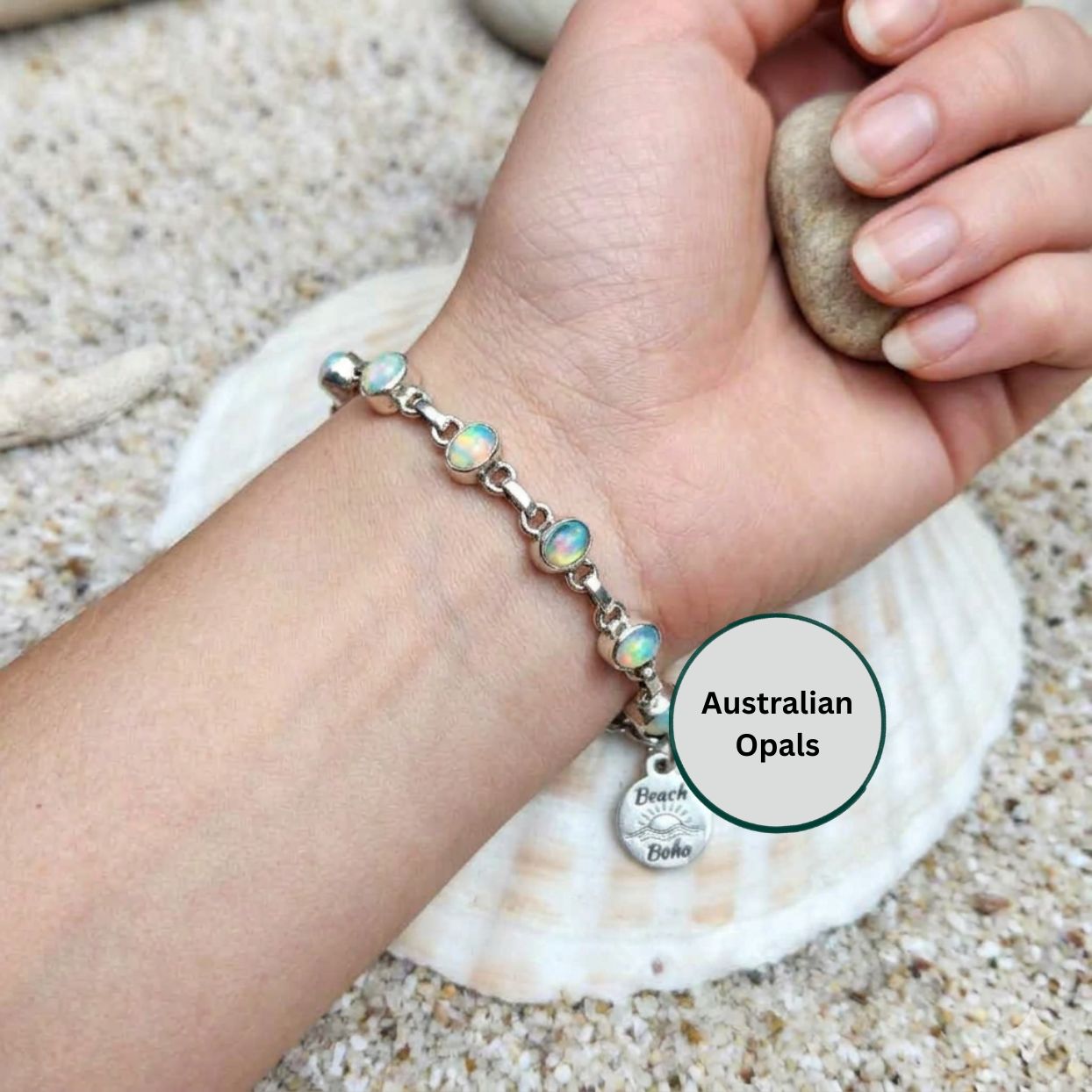 Hand wearing a bracelet with opal beads on a beach setting