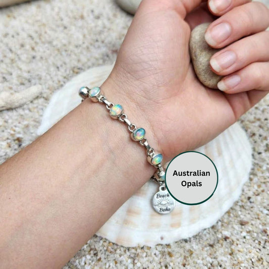 Hand wearing a bracelet with opal beads on a beach setting
