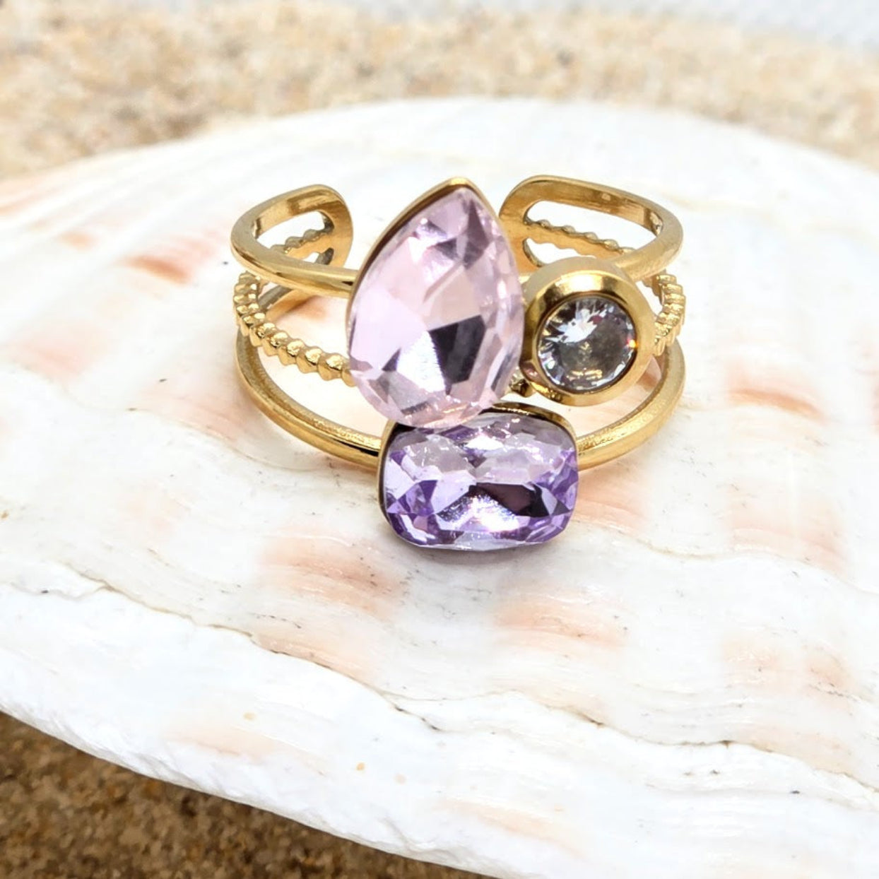 Gold ring with pink and purple gemstones on a shell