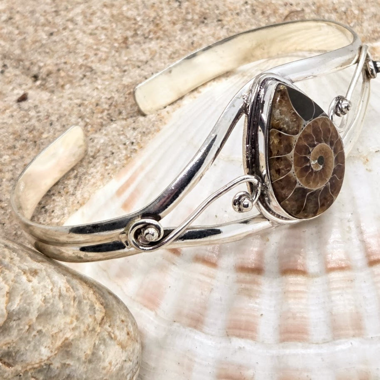 Silver bracelet with a fossilized ammonite on a shell background