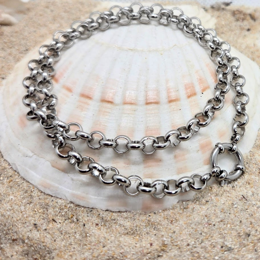 Silver chain necklace on a seashell with sand background