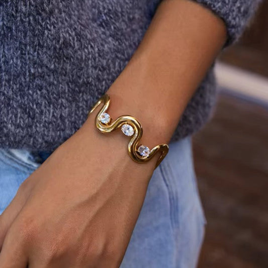 Gold bracelet with crystals on a wrist against a blurred background