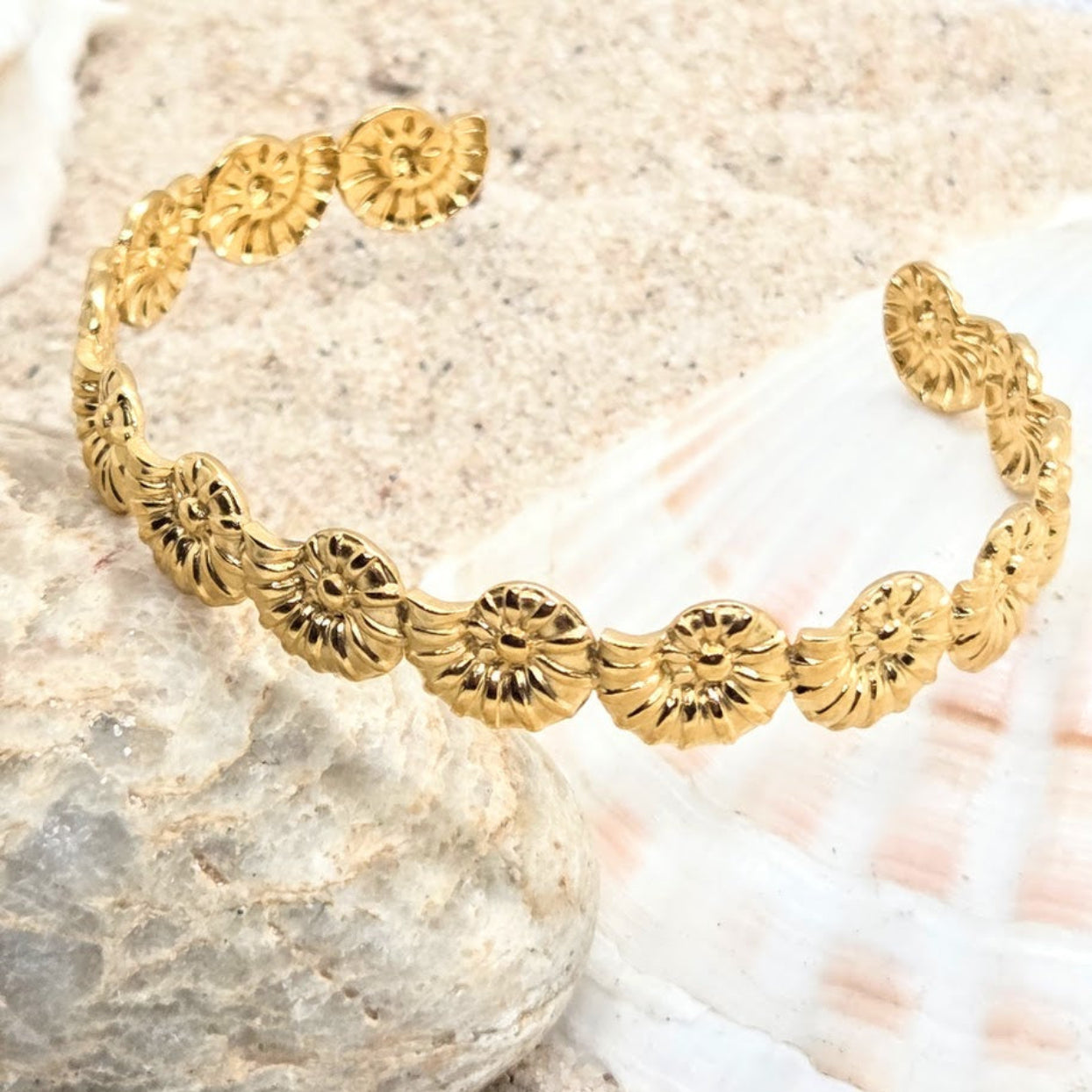 Gold bracelet with floral designs on a stone surface