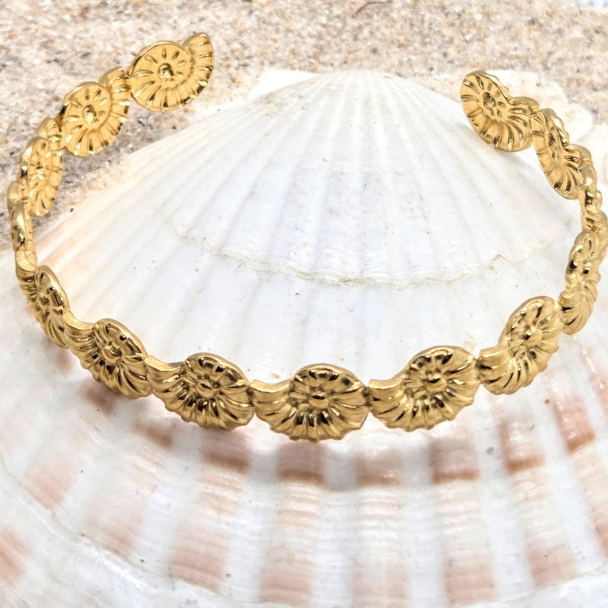 Gold bracelet with floral patterns on a seashell background