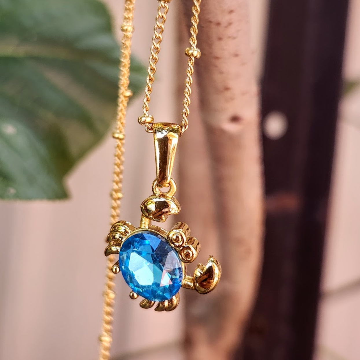 Gold necklace with a blue gemstone pendant against a blurred background