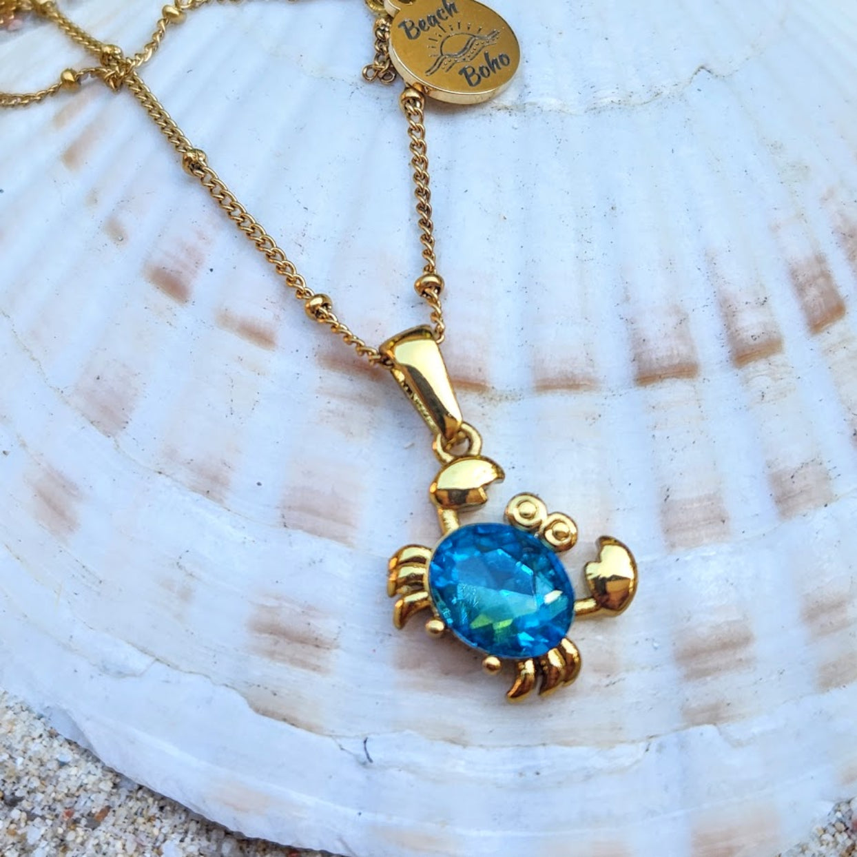 Gold turtle pendant necklace with blue gemstone on a shell background