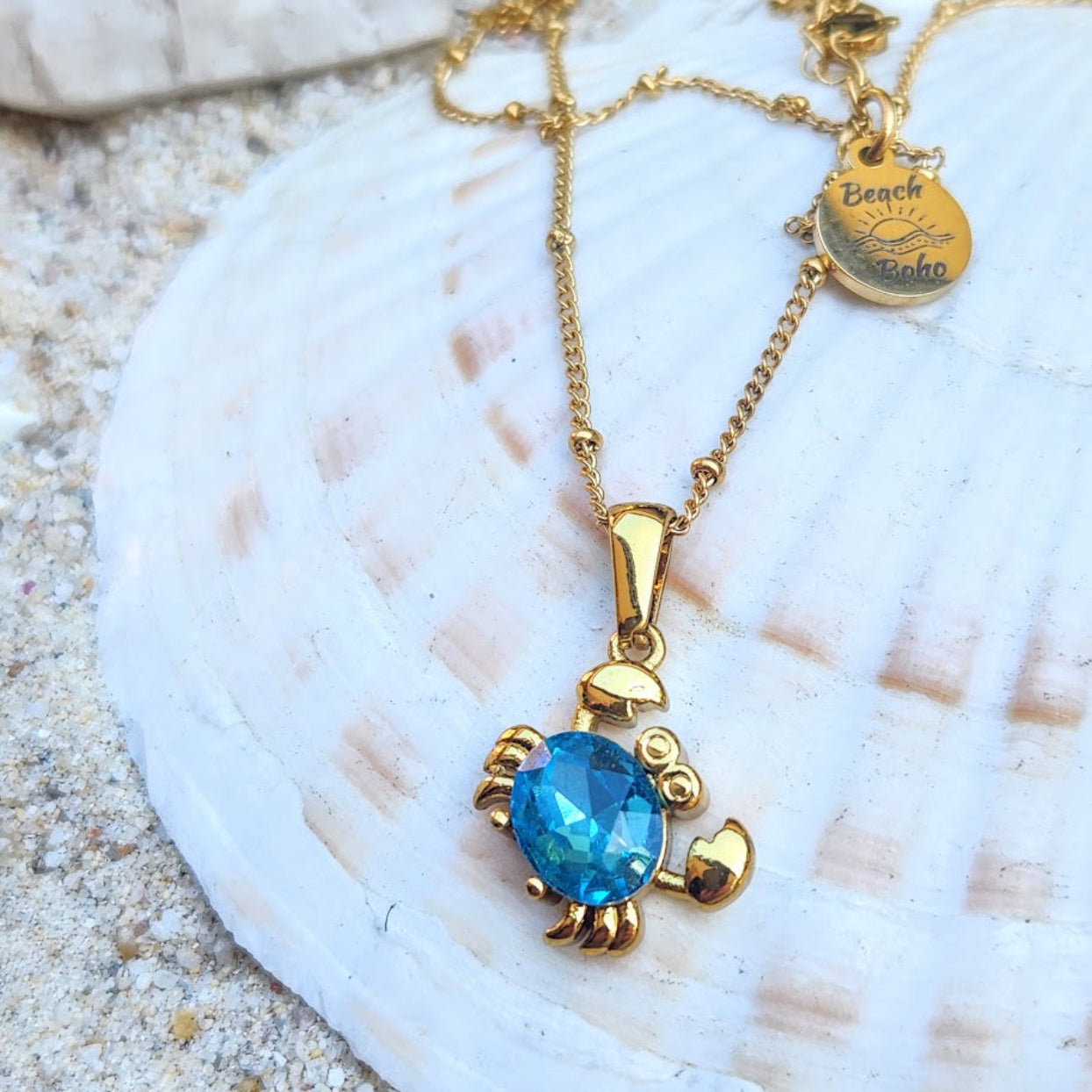 Gold necklace with a blue pendant on a seashell