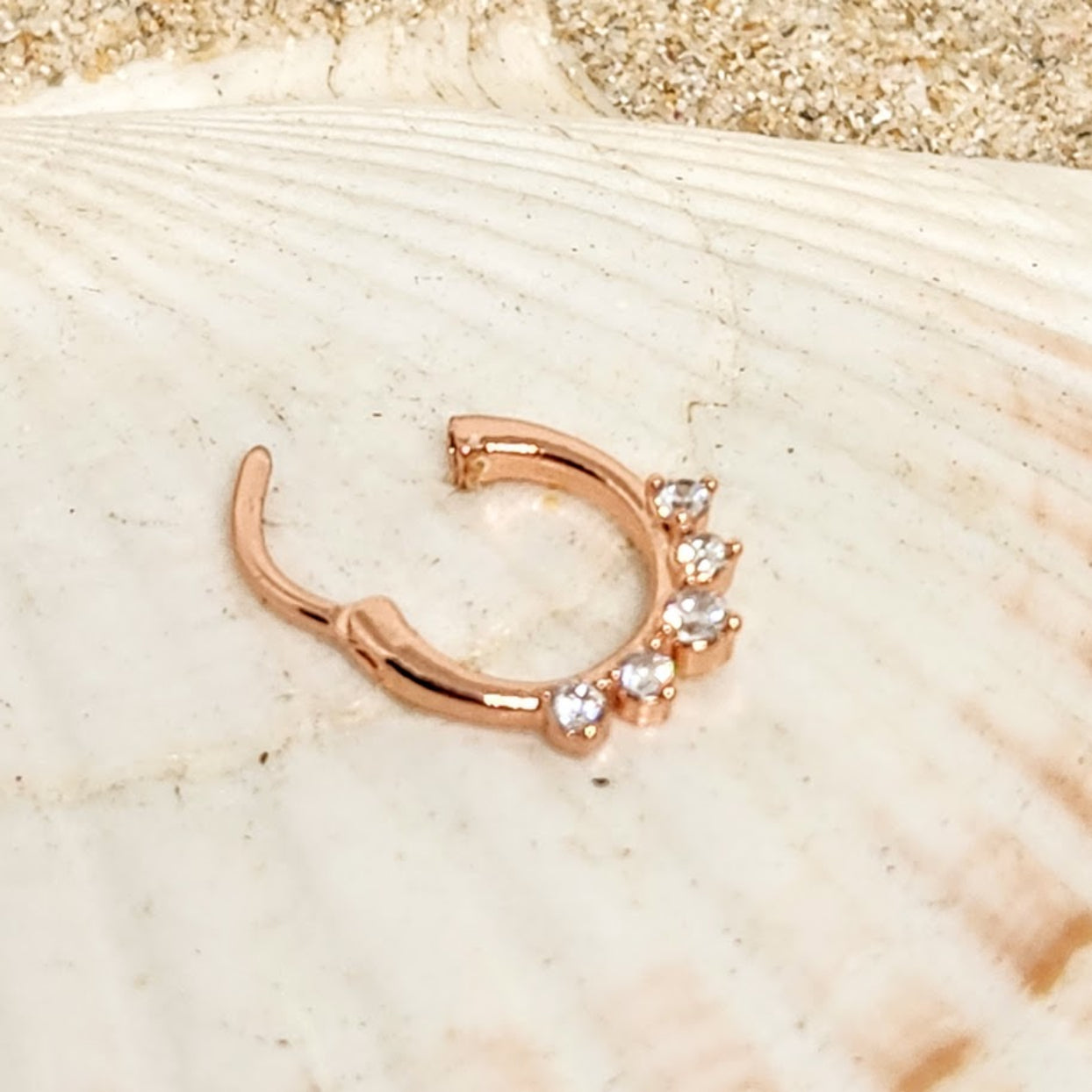 Rose gold nose ring with small diamonds on a shell background