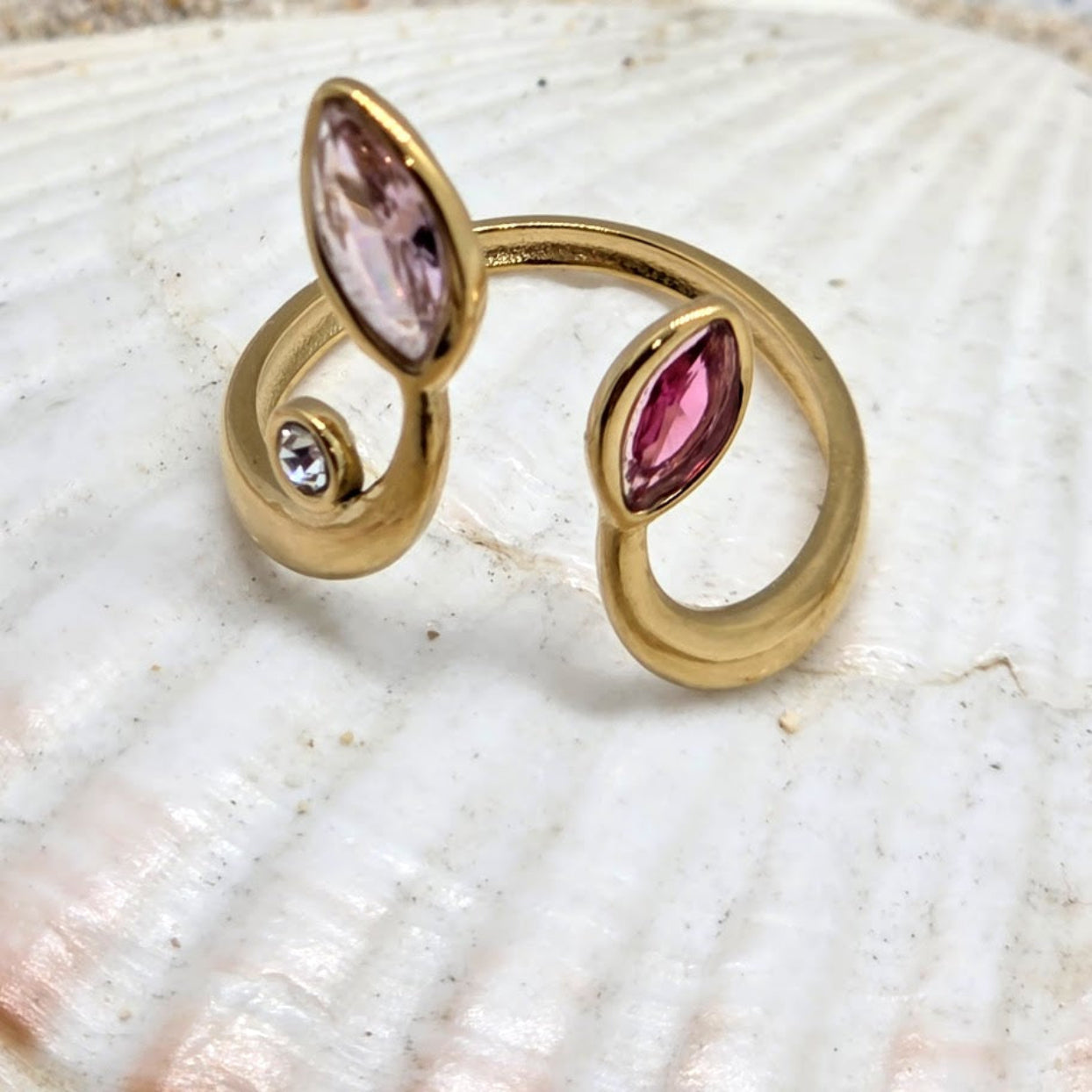 Gold ring with pink gemstones on a shell background