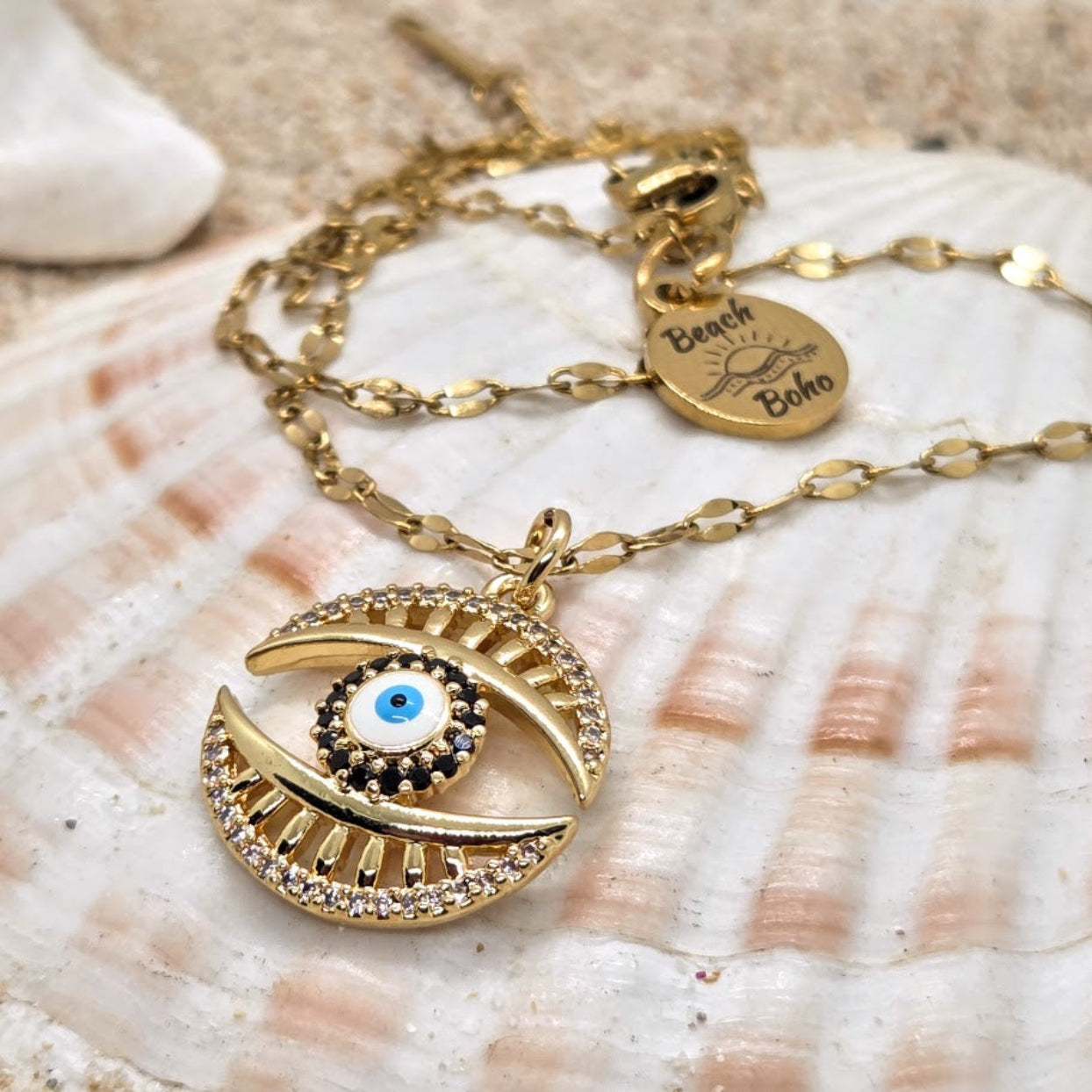 Gold necklace with an eye-shaped pendant on a shell background