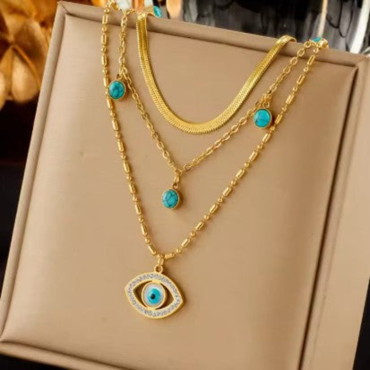 Gold necklace with turquoise stones on a beige box