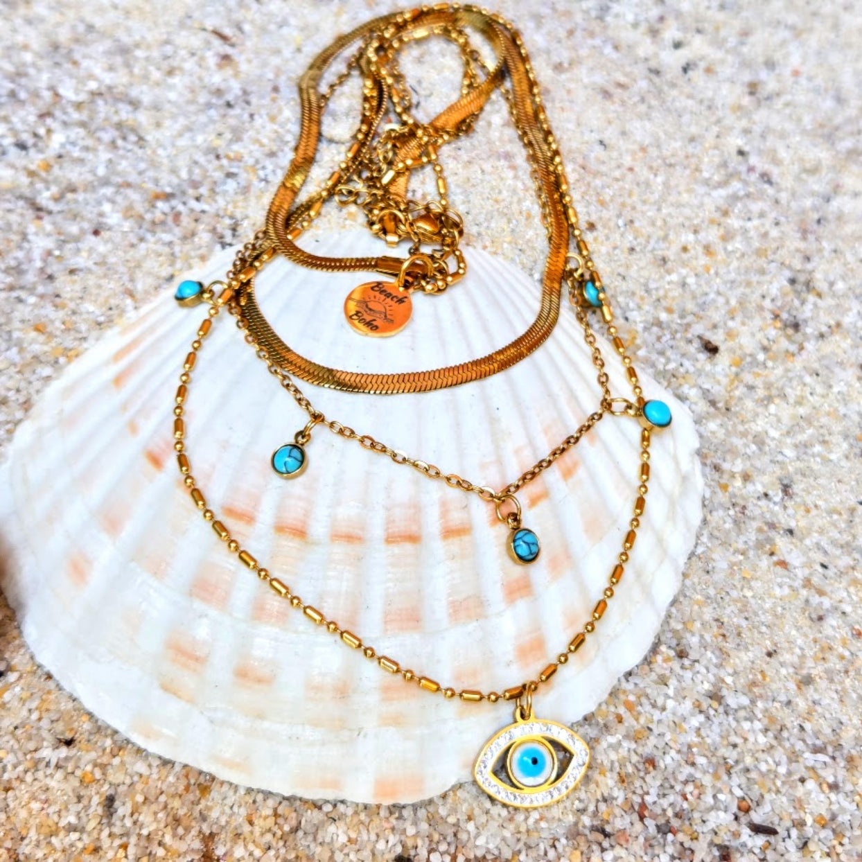 Gold necklace with blue stones on a seashell on sand