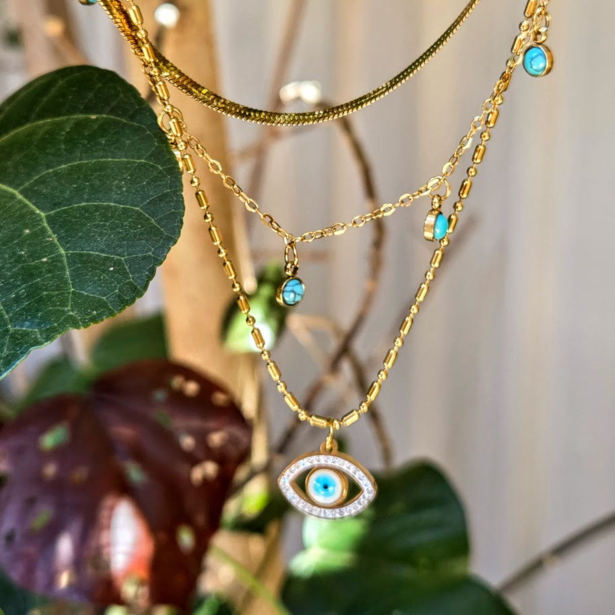Gold necklace with an eye-shaped pendant against a natural background