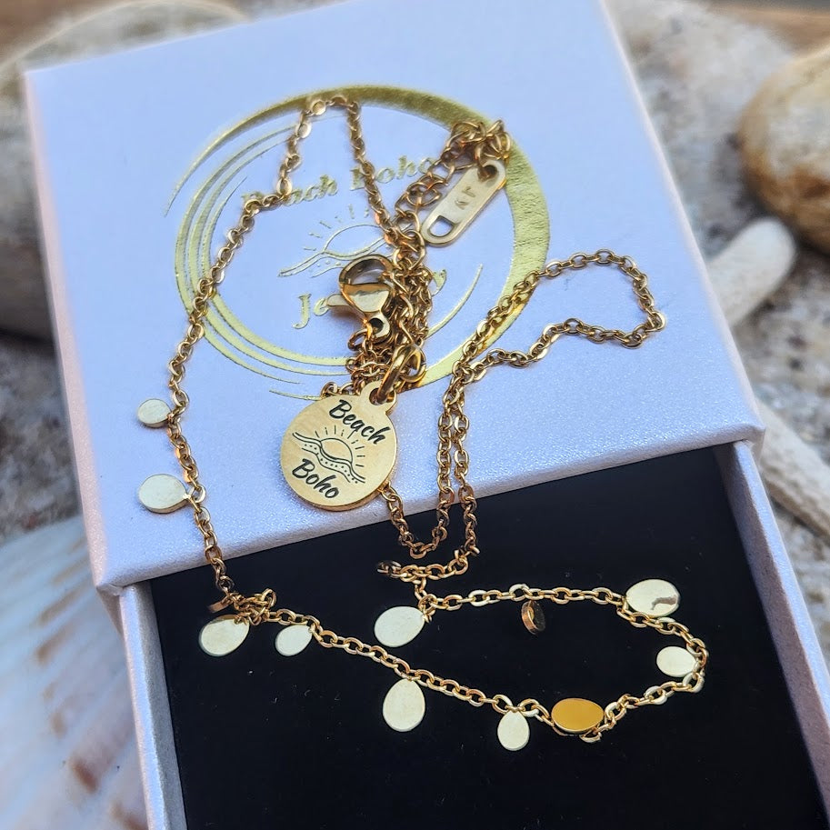 Gold necklace and bracelet set on a branded jewelry box with natural background