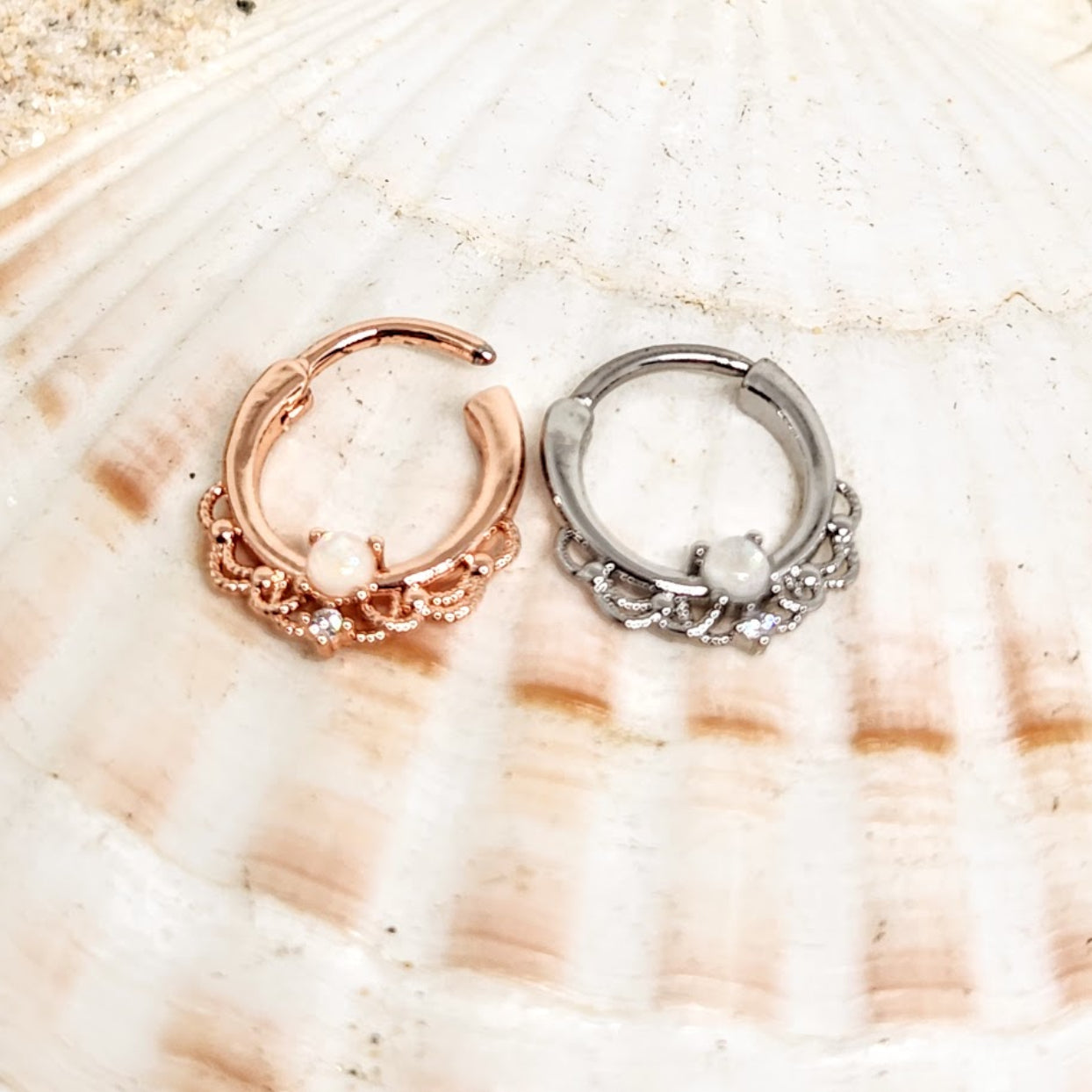Two hoop earrings, one rose gold and one silver, on a seashell background.