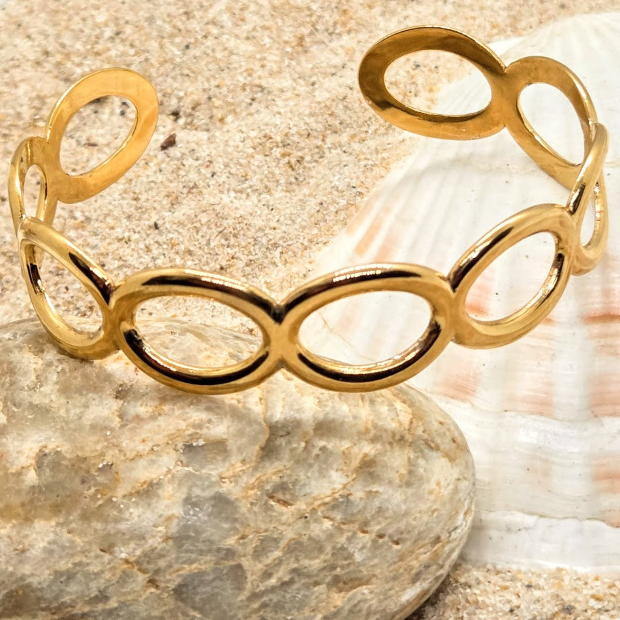 Gold bracelet on a stone surface with a shell in the background