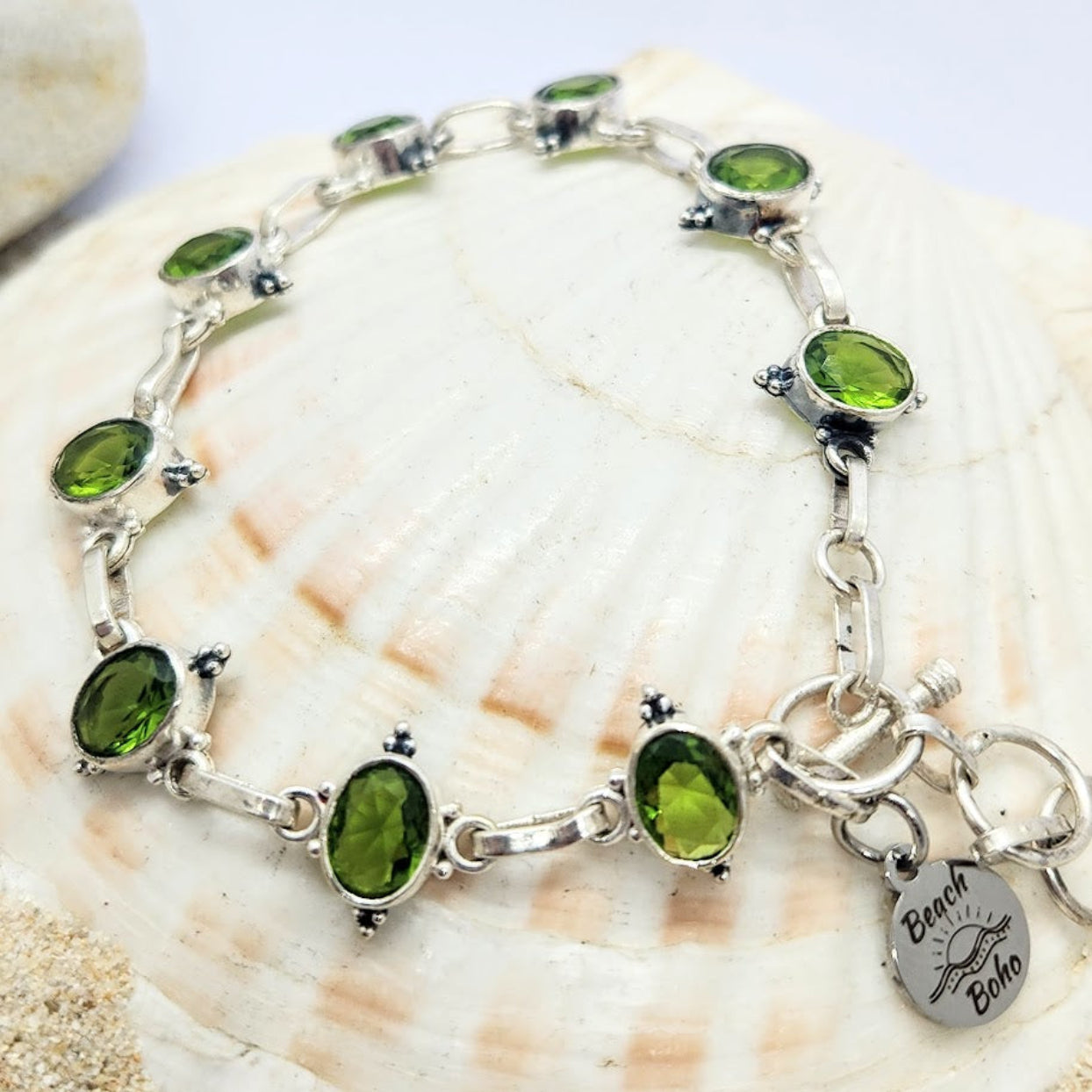 Silver bracelet with green gemstones on a seashell