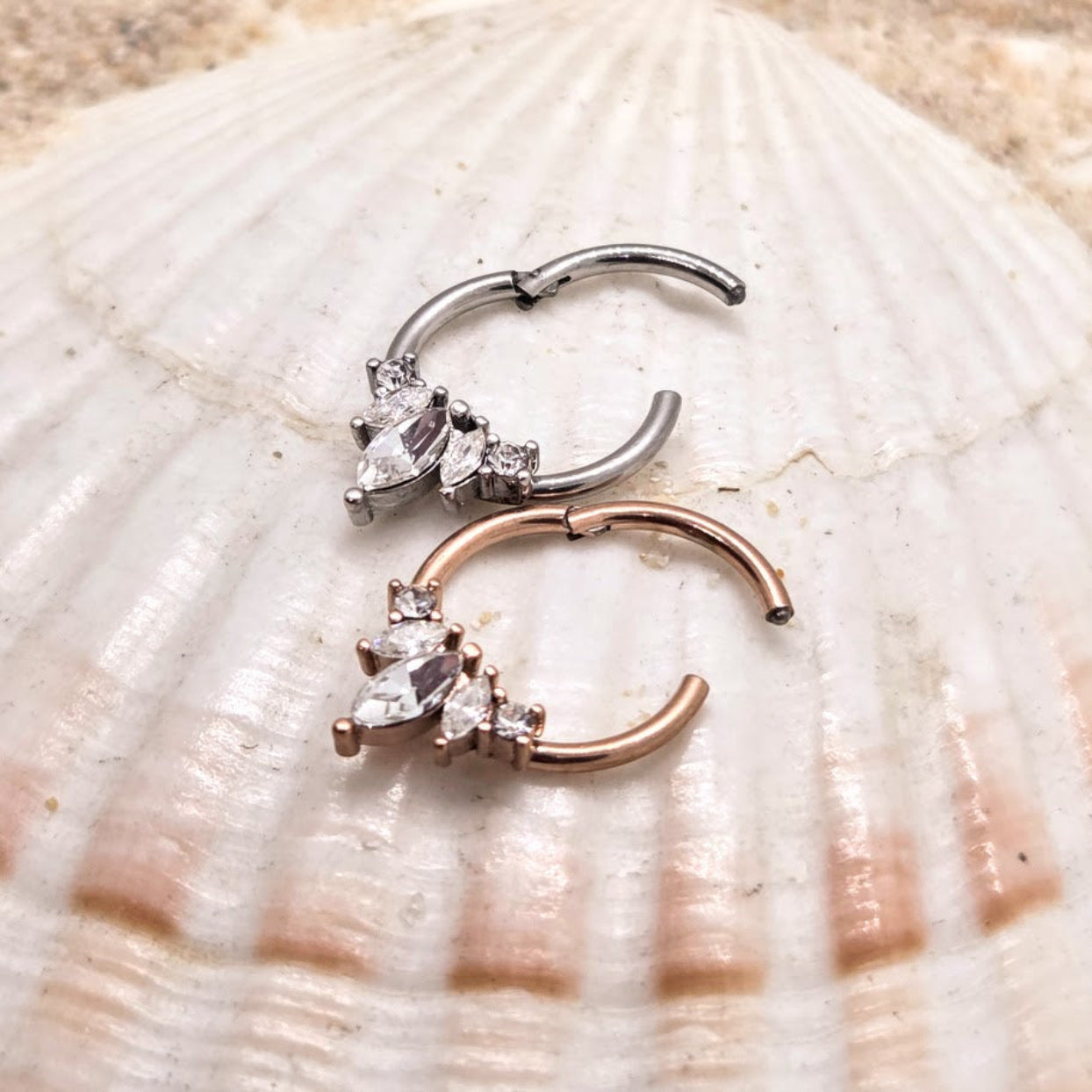 Two nose rings with gemstones on a seashell background
