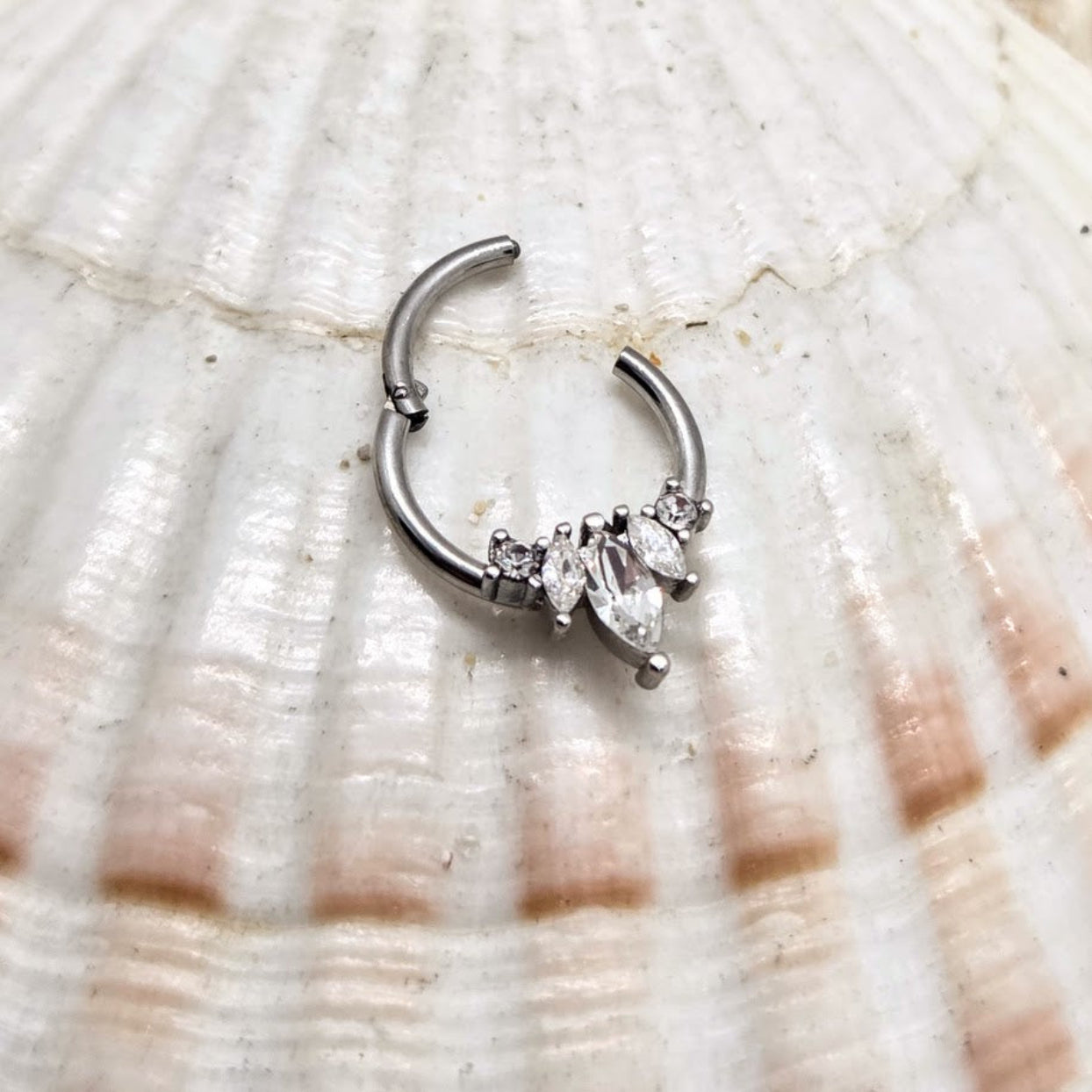Silver nose ring with marquise-shaped gemstones on a shell background