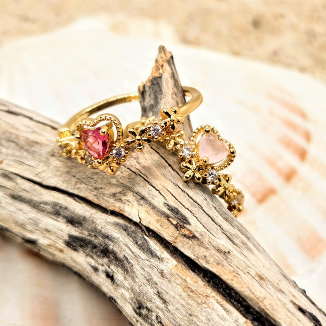 Gold rings with heart-shaped gemstones on a wooden surface