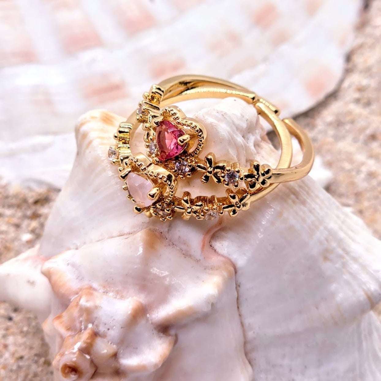 Gold ring with a red gemstone on a seashell