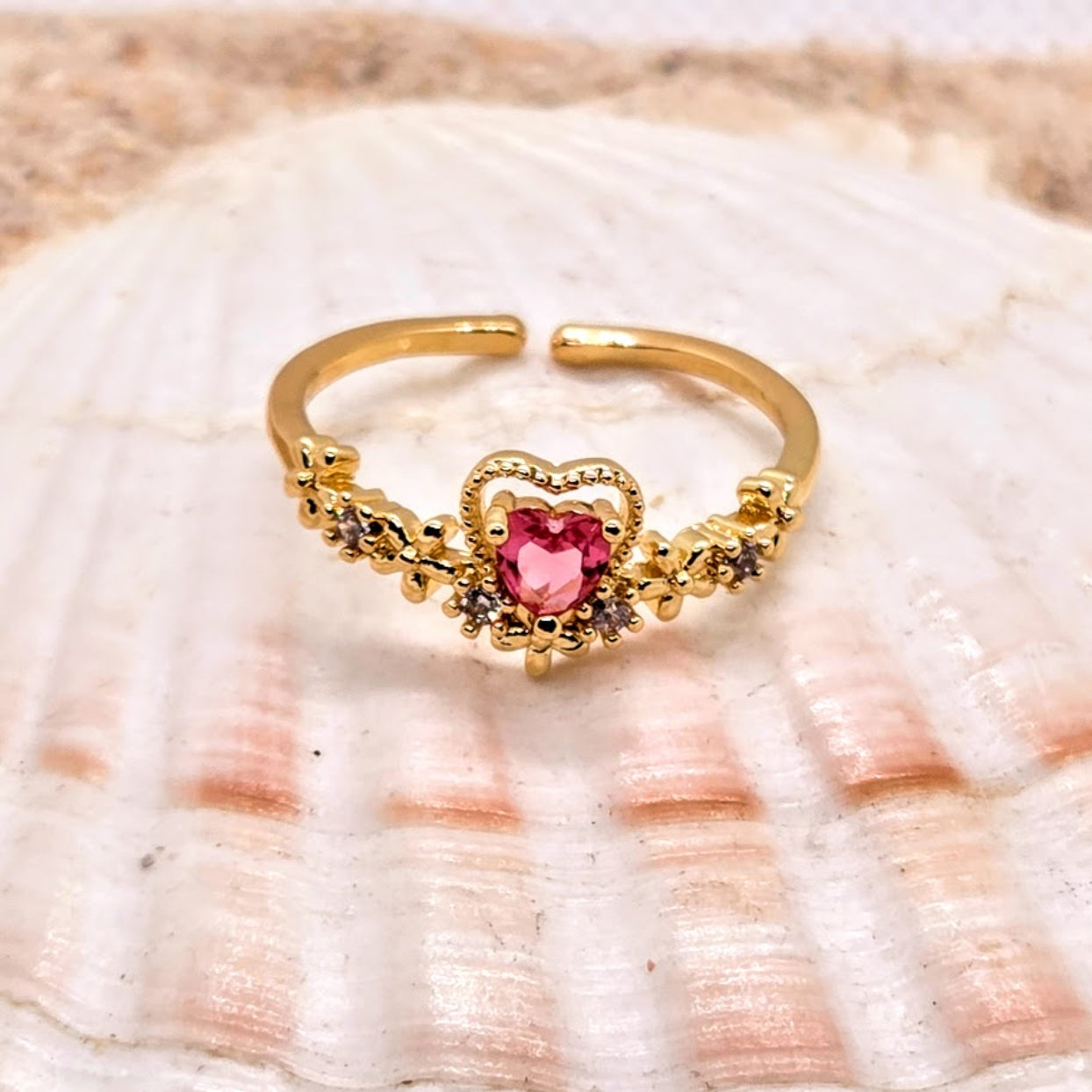 Gold ring with a pink heart stone on a seashell background