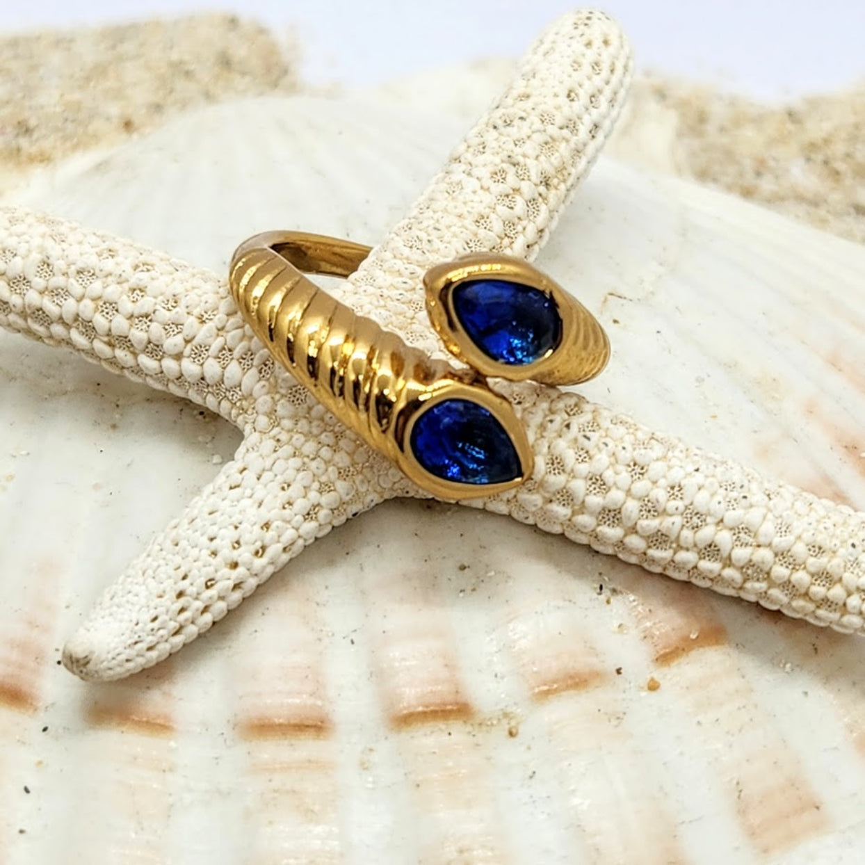 Gold ring with blue gemstone on a starfish and shell