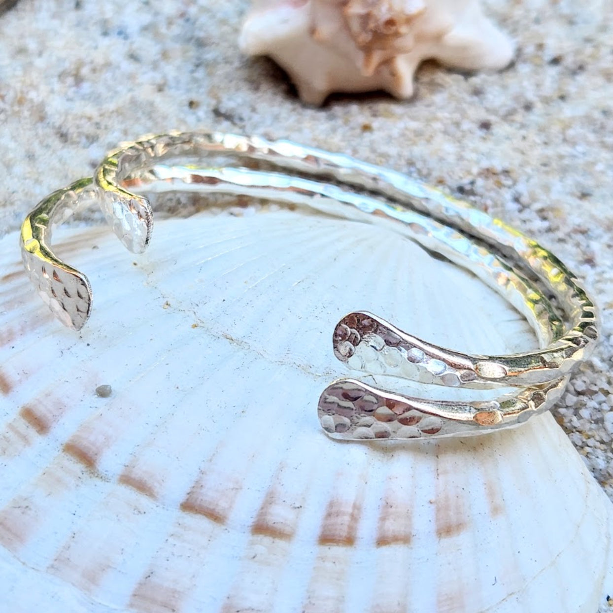 Silver bracelet on a seashell with a starfish in the background