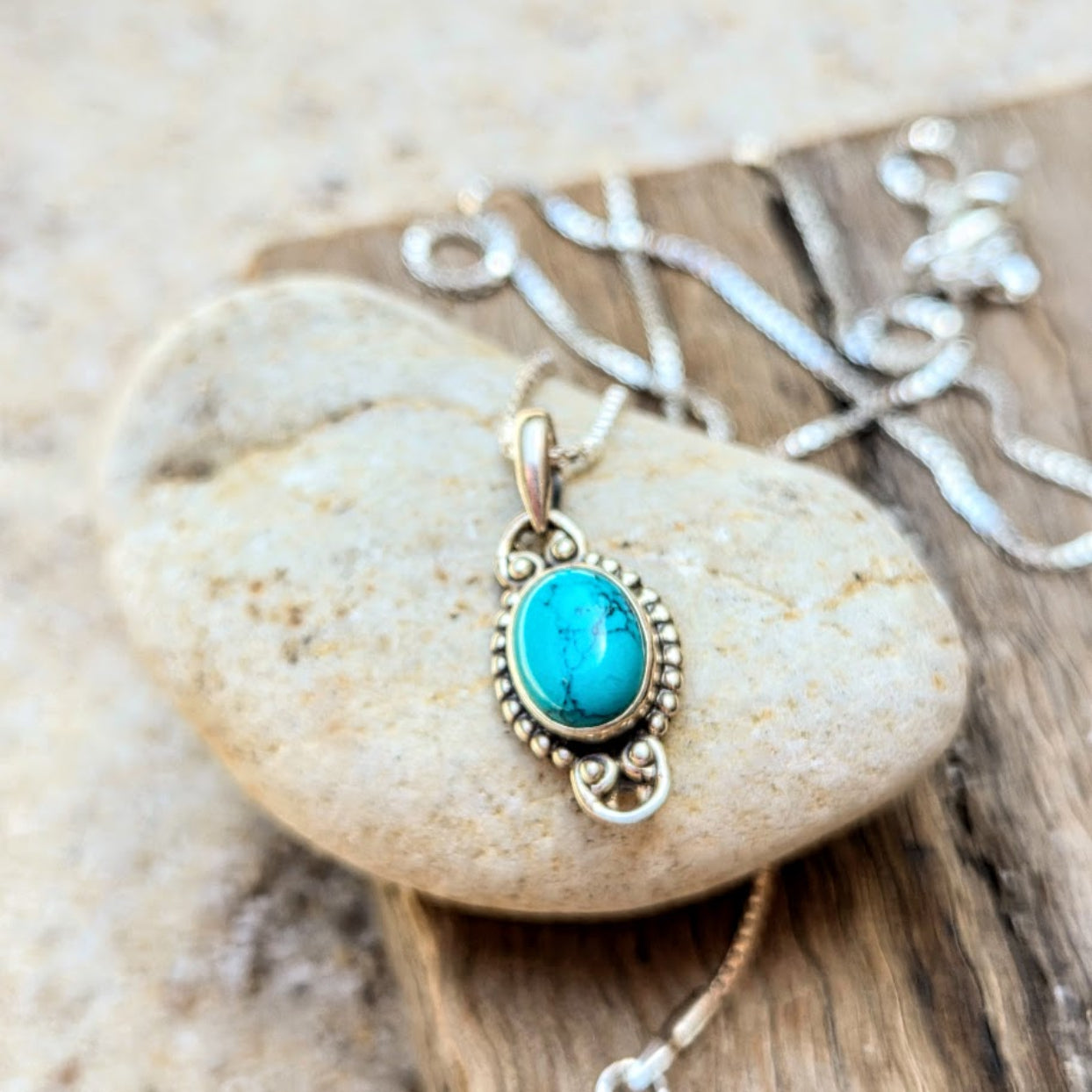 Turquoise pendant necklace on a stone surface