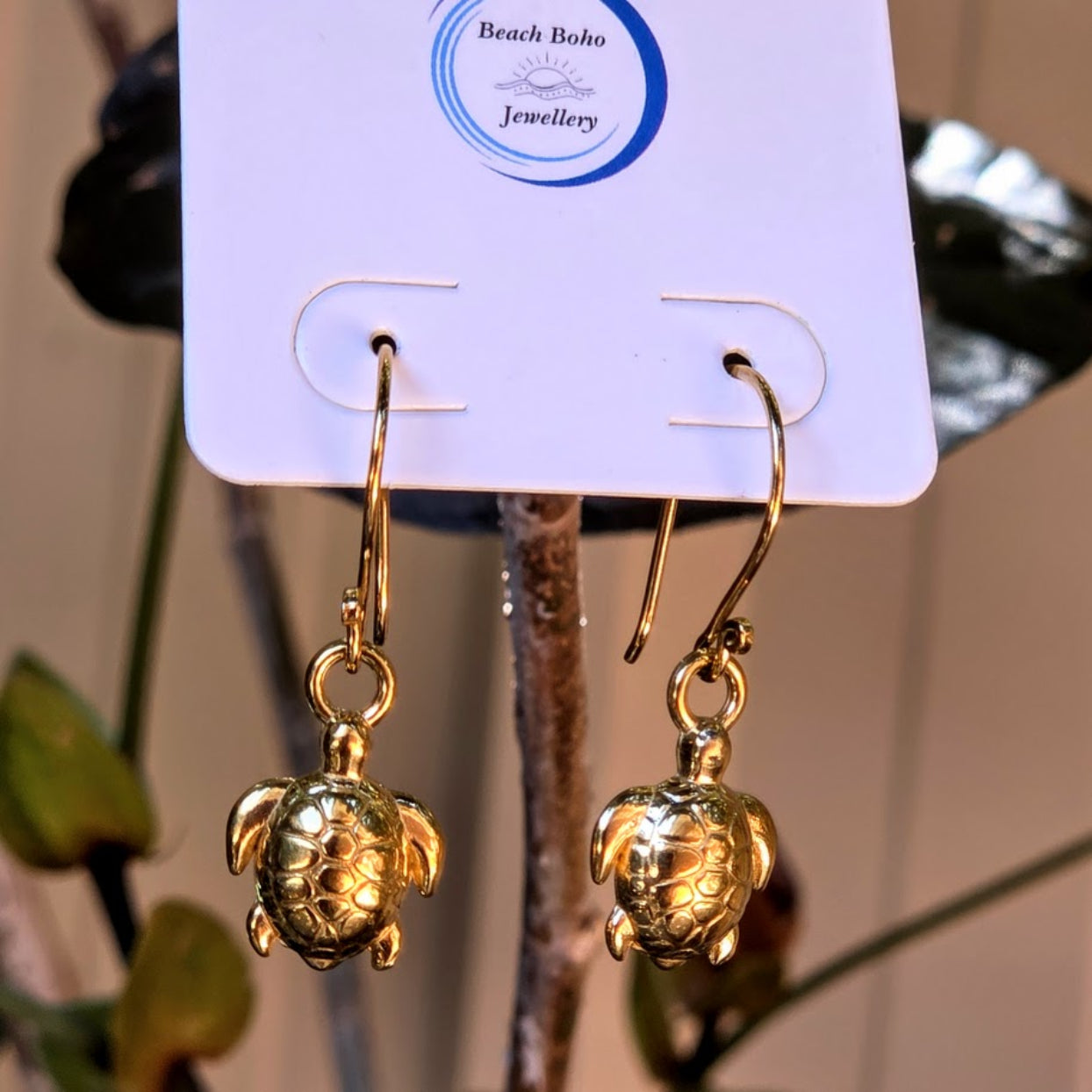 Gold turtle earrings on a Beach Boho Jewellery card with a blurred background