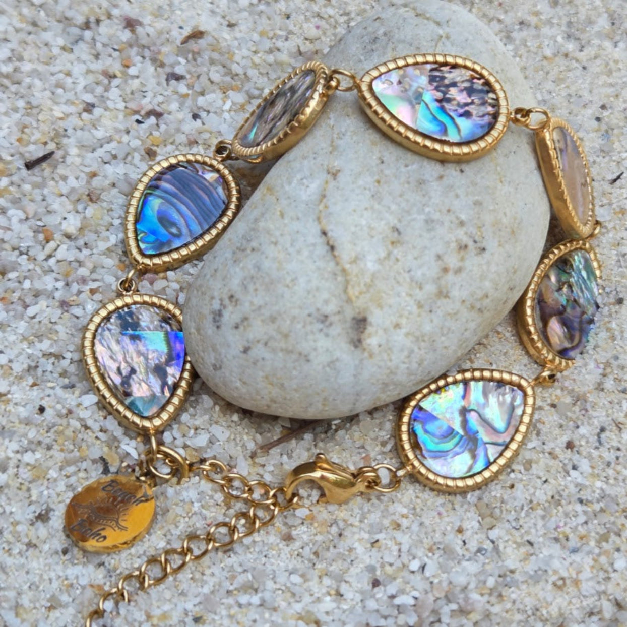 Gold bracelet with abalone shell beads on a stone surface