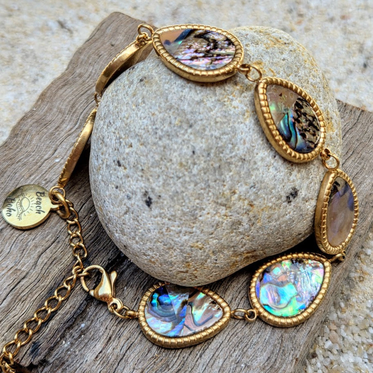 Gold bracelet with abalone shell stones on a stone surface