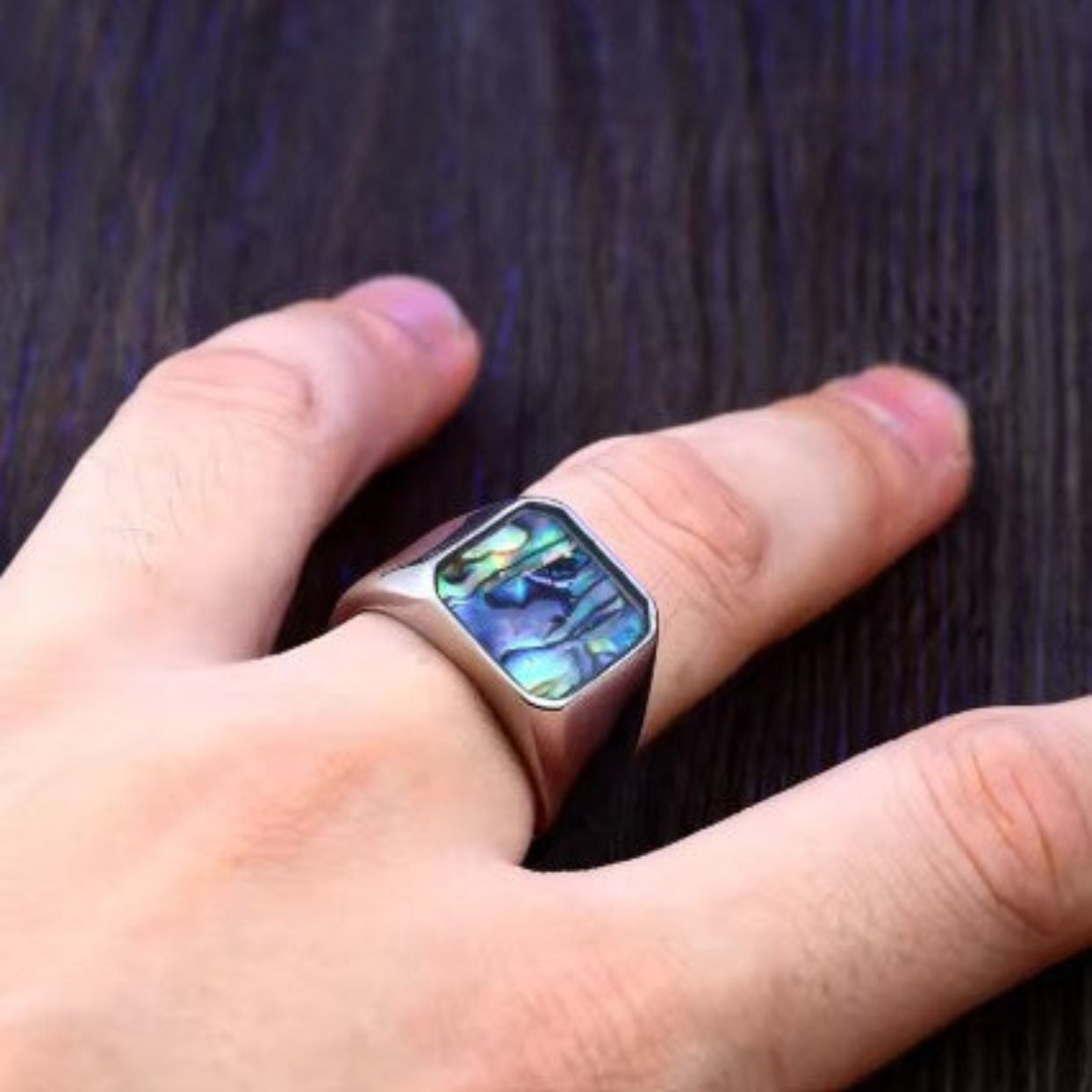 Smart ring with digital display on a finger against a dark background
