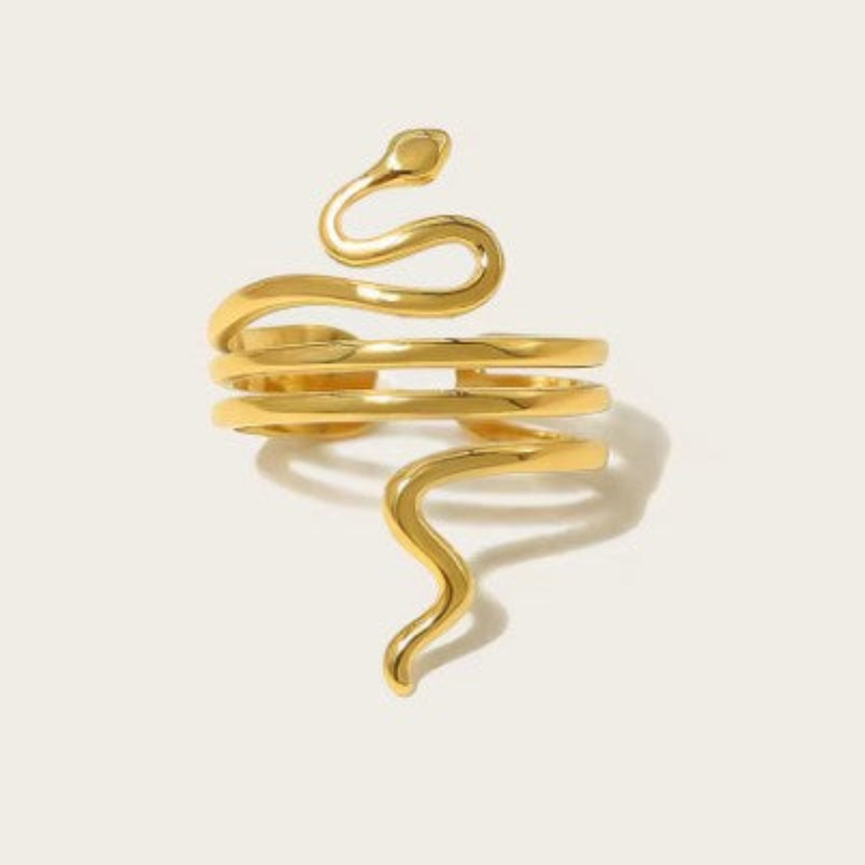 Gold snake-shaped ring on a light beige background
