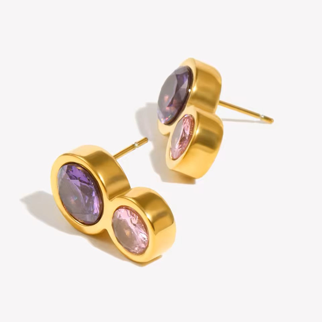 Gold earrings with purple and pink gemstones on a white background