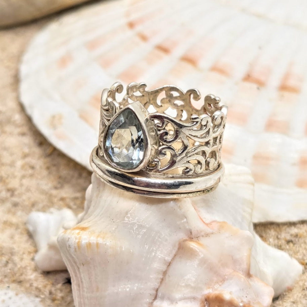 Silver ring with a clear gemstone on a seashell