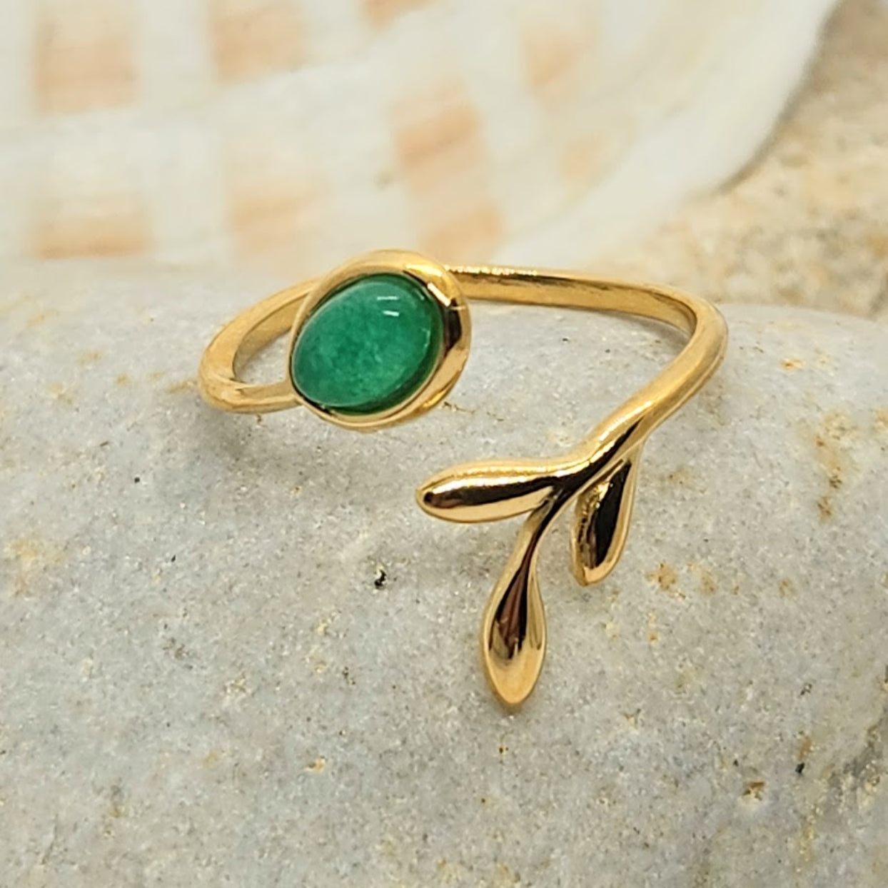Gold ring with a green gemstone on a stone surface