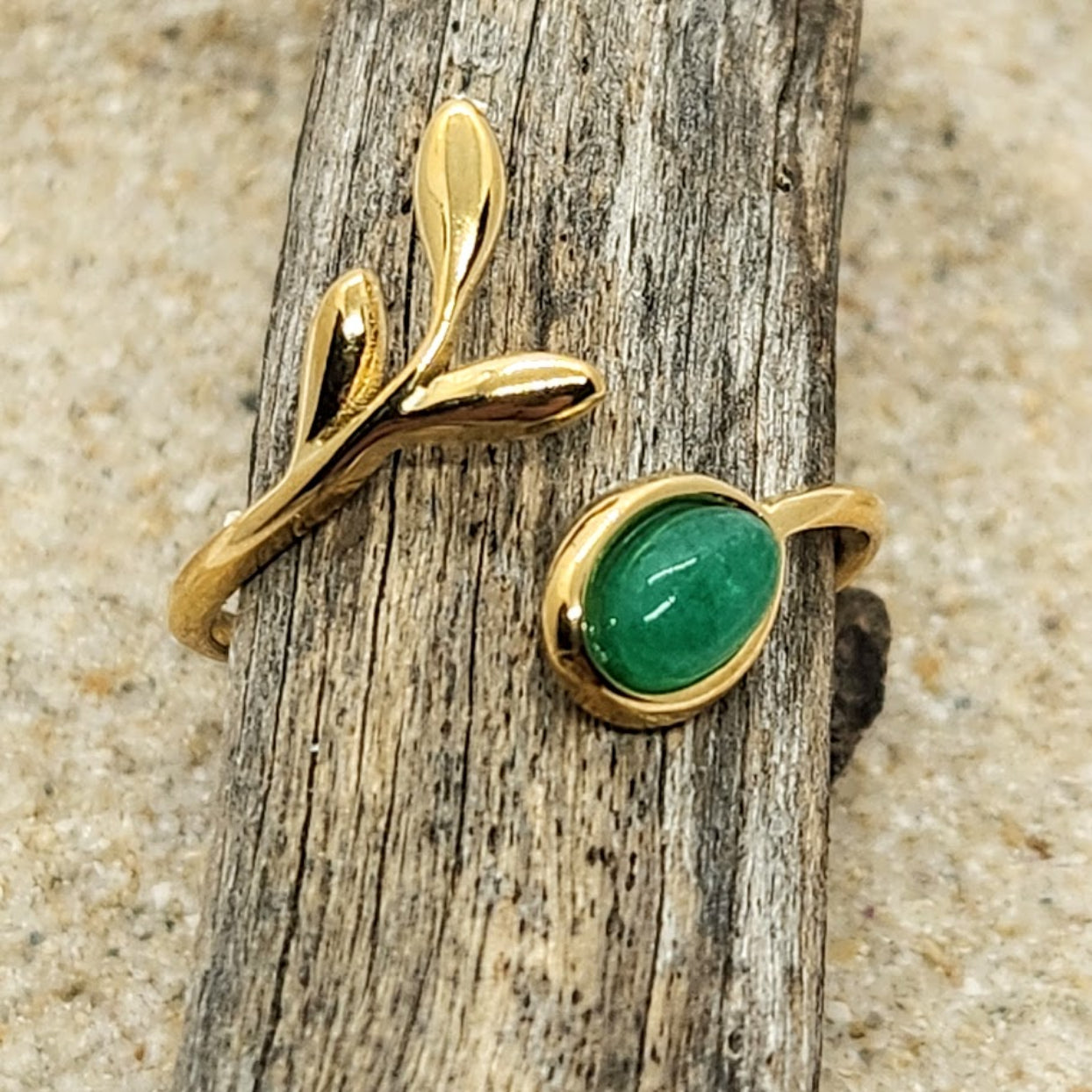 Gold ring with a green gemstone on a wooden stick