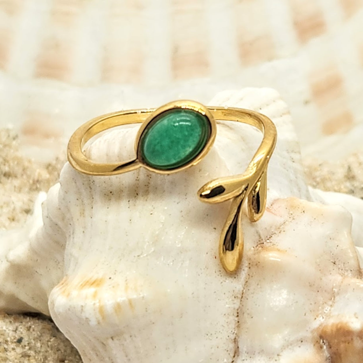 Gold ring with a green gemstone on a shell background