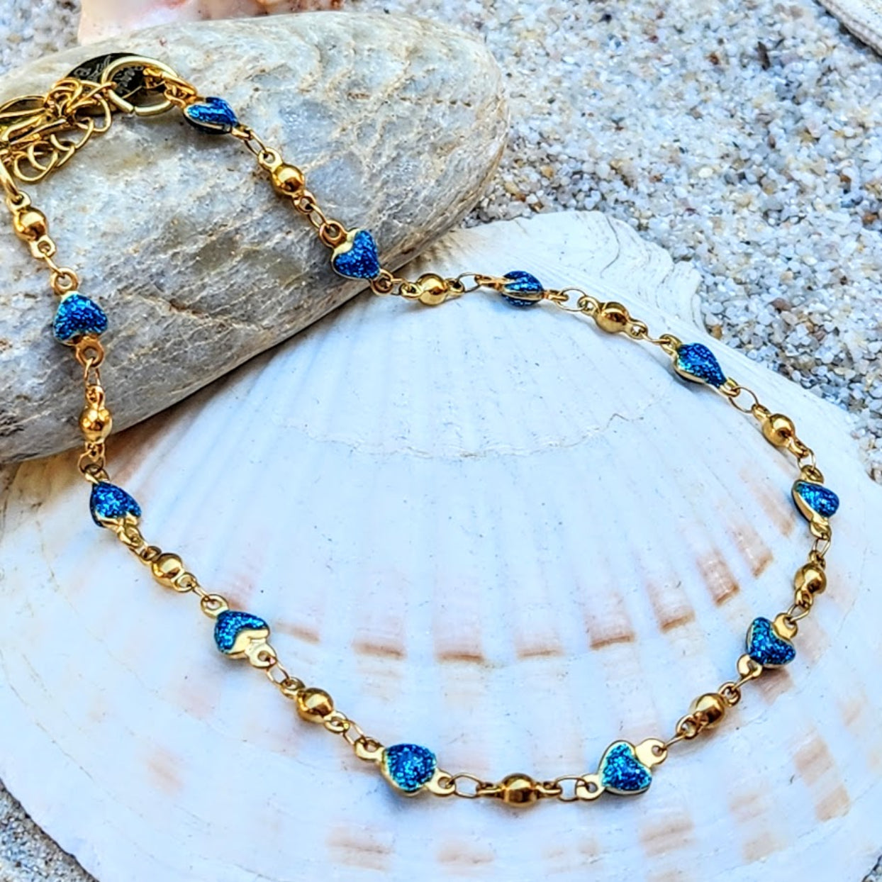 Gold bracelet with blue heart-shaped beads on a shell