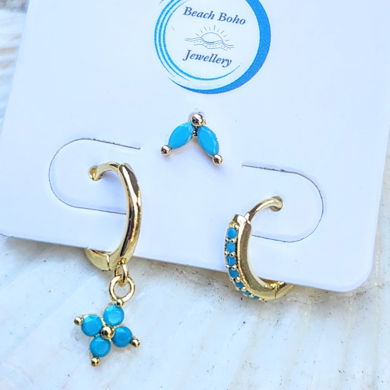 Gold hoop earrings with blue stones on a branded jewelry card.